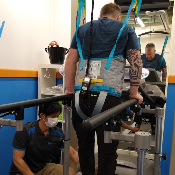 Man with a spinal cord injury learning to walk wearing a harness on a treadmill